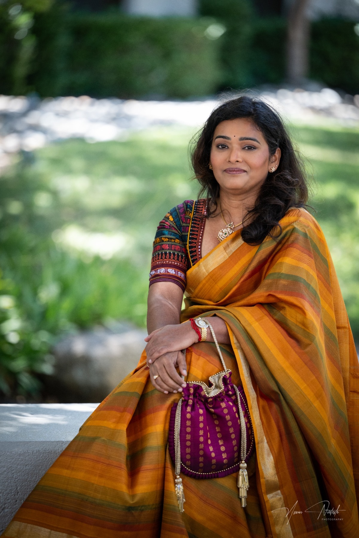 Subha with a purple potli and golden saree
