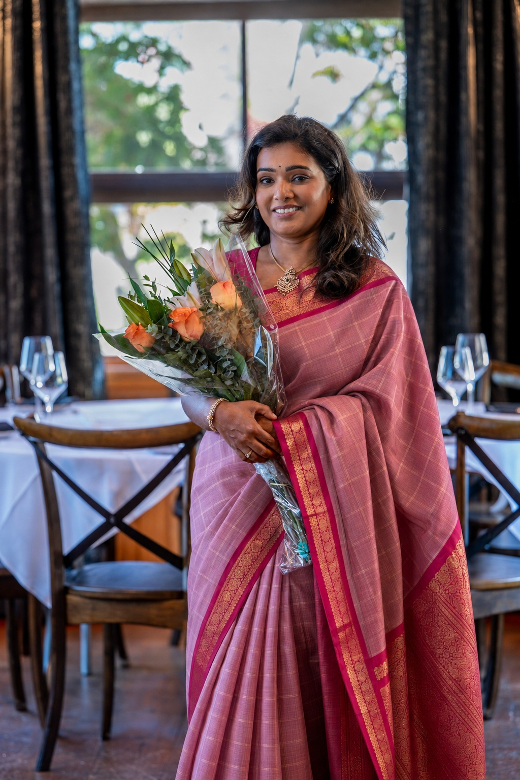 Subha wearing a pink saree and holding flowers