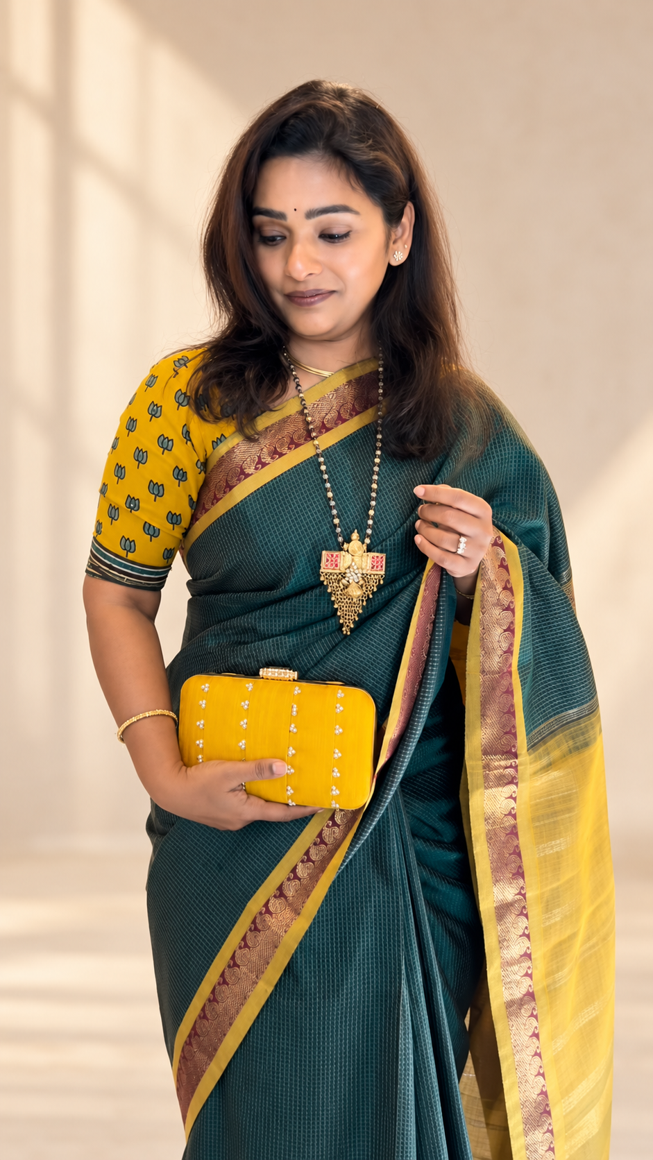 Subha in a yellow lotus blouse and green saree holding a yellow clutch